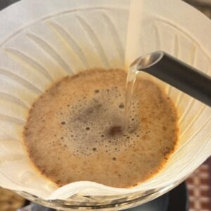 close-up of coffee in a filter with water being poured over it