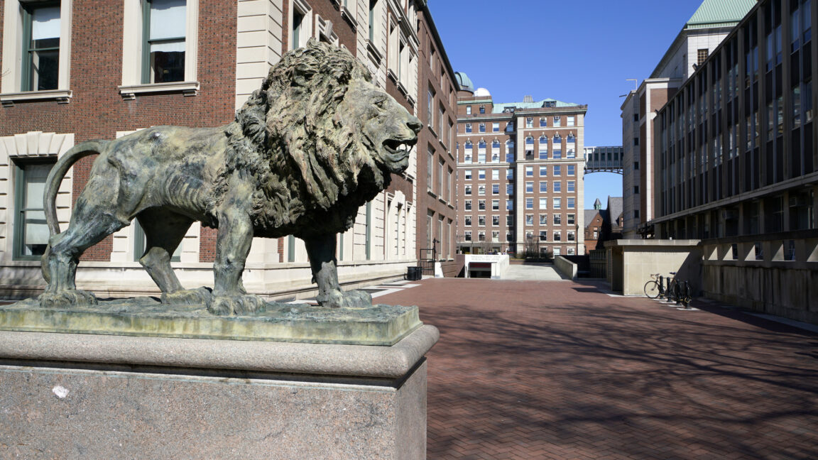 A lion statue in front of a brick plaza, surrounded by red brick buildings.